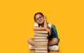 Korean Schoolgirl Sitting At Books Stack In Studio, Yellow Background Royalty Free Stock Photo