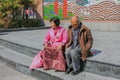 Korean senior people. Tired asian elderly couple sitting and resting on steps of urban street stairs.