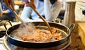 Korean spicy Kimchi bbq pork served on a hot pan with side dishes and rice as a background.