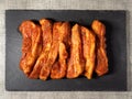 Korean style marinated pork belly slices, close up, on a black stone plate. Fresh meat preparation. Top view Royalty Free Stock Photo