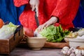 Korean women wear traditional red hanboks, make kimchi by slicing Chinese cabbage.