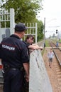 A policeman talks to a drunken citizen on a railway platform.