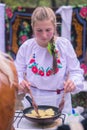 Korosten, Ukraine - September 06, 2016: open kitchen young woman pouring oil into frying potato pancakes. Royalty Free Stock Photo