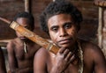 Korowai tribe woman smokes a traditional pipe. Tribe of Korowai Kombai , Kolufo.