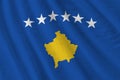 Kosovo flag with big folds waving close up under the studio light indoors. The official symbols and colors in banner