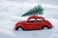 Kostanay, Kazakhstan 2022.Red Volkswagen beetle with spruce on roof, against background white snow Royalty Free Stock Photo