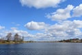 The Kostroma River. On the high banks are village houses, trees and green grass. There are white clouds in the blue sky. Wind