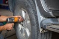 Unidentified man hand making tyre fitting with air compressed wrench screwing up bolts