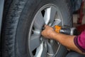 Unidentified man hand making tyre fitting with air compressed wrench screwing up bolts