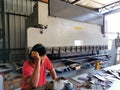 A worker taking rest in front of bending machine in the factory.