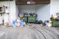 Huge garbage piles next to the dumpster. Overflow garbage