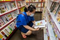 Portrait woman with medical face mask choosing a book in a bookstore