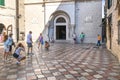 Tourists play with a cat as a beggar asks for money on the steps of the St Nicholas Church in Kotor Montenegro