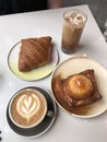 Kouign-amann tabled with a croissant, hot coffee and iced-coffee Royalty Free Stock Photo