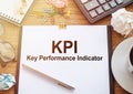KPI short for Key Perfomance Indicator text on a clipboard with coffee, calculator, glasses, crumpled sheets and notebook Royalty Free Stock Photo
