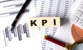 KPI text on wooden block on graph background with pen and magnifier Royalty Free Stock Photo