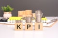 KPI text in wooden blocks with coins stacked in increasing stacks. Key Performance Indicators concept Royalty Free Stock Photo