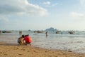 Children playing sand and some people walking and relaxing at Ao Nang beach before the sunset Royalty Free Stock Photo