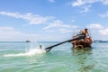 Krabi, Thailand - February 12, 2019: The driver of a longtail motorboat drives a motor with a long drive and a propeller. Sailor