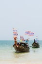 Krabi, Thailand - March 2019: long tail wooden boats with Thai flags moored at Railay beach