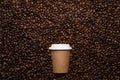 Kraft disposable cup to go, on the background of coffee beans with empty space for text. Royalty Free Stock Photo