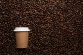Kraft disposable cup to go, on the background of coffee beans with empty space for text. Royalty Free Stock Photo