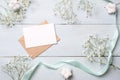 Kraft envelope with blank card for invitation or congratulation and bunches of flowers on light blue wooden background. Female wed Royalty Free Stock Photo