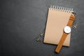 Kraft notebook and stylish wristwatch on black table. Space for text