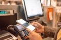 Krakow, Poland - April 26, 2022: Side view of young woman paying at self-checkout using smartphone app at store Royalty Free Stock Photo