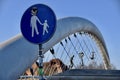 Krakow, Poland. Blue Circular Street Sign with adult holding childs hand. Father Bernatekâs Bridge behind.