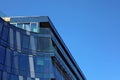 KRAKOW, POLAND, 2021 - Corner fragment of office building facade made of toned glass and steel constructions under blue sky.