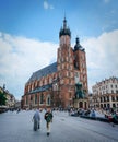 KRAKOW, POLAND - JUNE 28, 2016: People walk in front of St. Mary Church (Mariacki Church) on main market square on nice summer Royalty Free Stock Photo