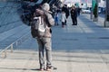 Krakow, Poland 04.01.2019: A man in dark clothing with a large backpack stands and looks at his phone in a public place. waiting.