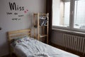 Rented room of a female student.A single made-up bed, an inscription on the wall and a wooden bookcase