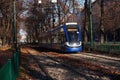 Krakow, Poland 16.12.2021: Sunny warm autumn weather in city, tram view in gallery with dried leaves on ground, grey trees. Urban