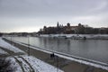 Krakow, Poland - Wide angle view of famous wawel castle covered with snow next to vistual river against cloudy Royalty Free Stock Photo