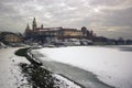 Krakow, Poland : Wide angle view of famous wawel castle covered with snow next to vistual river against dramatic Royalty Free Stock Photo