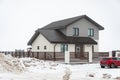 Krasnodar, Russia - January 23 2021: Two-story private house surrounded by a fence and a red car