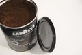 Can of ground coffee, band name Lavazza, surface.