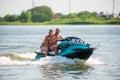 Couple of men drives Yamaha Waverunner jet ski at sunset by river bank at countryside. Extreme sports and active summer vacation