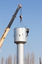 A crane installs a water tower.