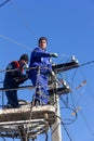 Male electricians change electrical wires on poles Royalty Free Stock Photo