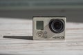 An old worn and dusty GoPro Hero 3 action camera, on a wooden background with a long shadow. Close-up