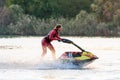 Beautiful Caucasian jet ski sportsman woman driving superjet watercraft splashing in sunset