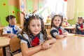 First-form schoolchildren in classroom at school desks on holiday of beginning of elementary school education. Happy girls at