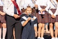 First-form schoolgirl at school on holiday of beginning of elementary education reading poetry. Girl with microphone declaiming Royalty Free Stock Photo