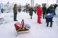 Small child is lying in a wheelchair-sled against the backdrop of a crowd of people in an ice-filled amusement park.