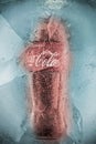 Krasnoyarsk, Russia, August 16, 2020: a Bottle of Coca Cola frozen in a block of ice. Greenish background