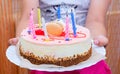 Hands of a child holding a birthday cake. There are eight candles on the cake. The candles are Royalty Free Stock Photo