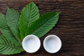 Kratom Mitragyna speciosa Mitragynine leaves with empty white ceramic bowls on wooden Royalty Free Stock Photo